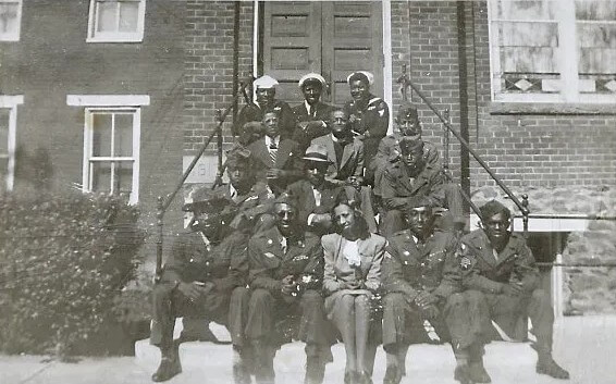 Historic photo of a group of military service members posing on brick building steps