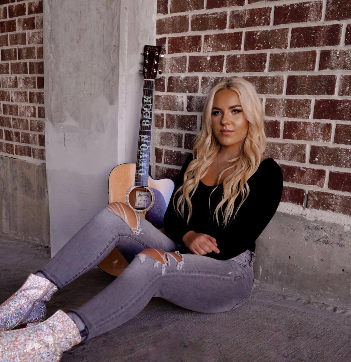 Country singer sitting on ground with guitar