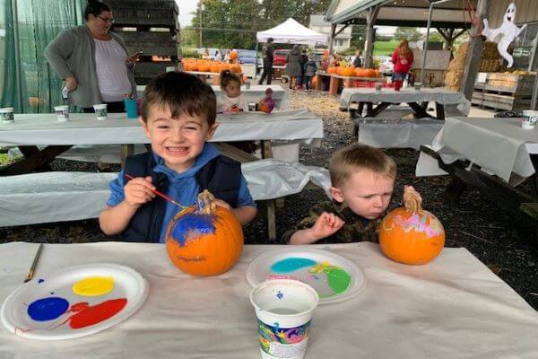 two young boys painting pumpkins